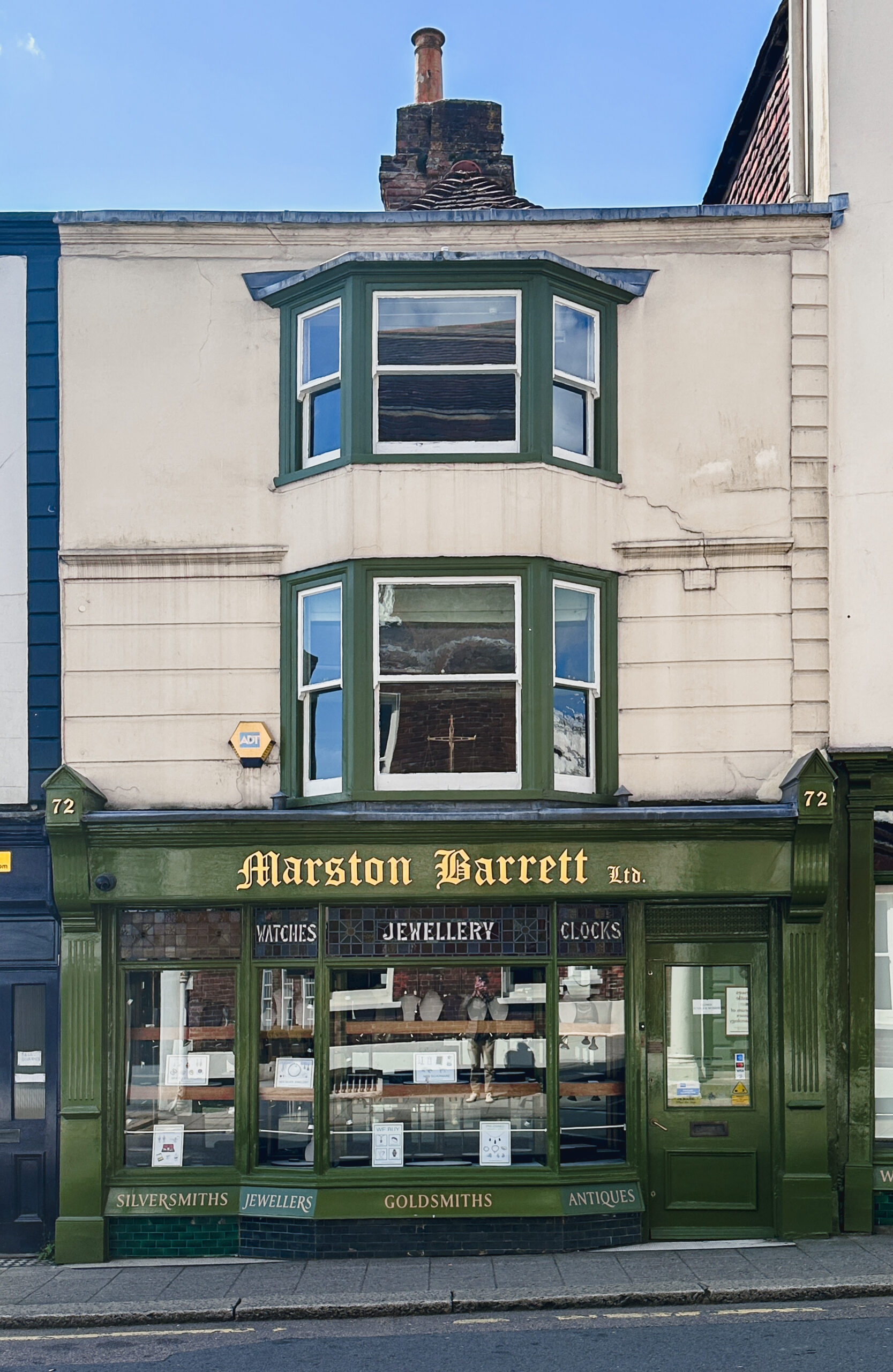 The green-and-gold Victorian shopfront of Marston Barrett Ltd at 72 High Street, Lewes, with gilt lettering reading WATCHES JEWELLERY CLOCKS across the bay window